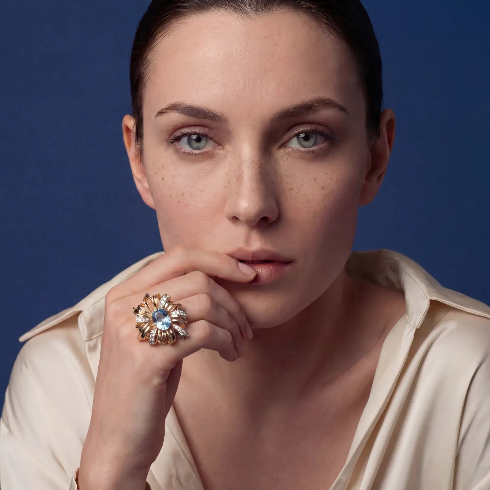 The aquamarine ring worn, a hand at the chin